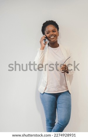 Photo of young african woman communicate on mobile phone while drinking iced coffee standing isolated over white color background.