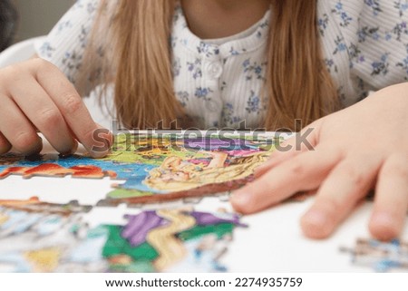 Little child picks up picture from pieces of puzzles, concept of education