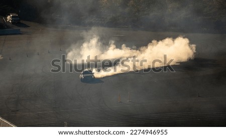 Drifting car drifting with billowing smoke trails golden sunrise fast cars Royalty-Free Stock Photo #2274946955