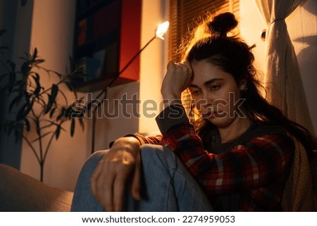 Portrait of sloppy depressed young Caucasian woman is sitting on sofa suffering from psychological problems. Evening home. Depression and mental disorder. Royalty-Free Stock Photo #2274959053