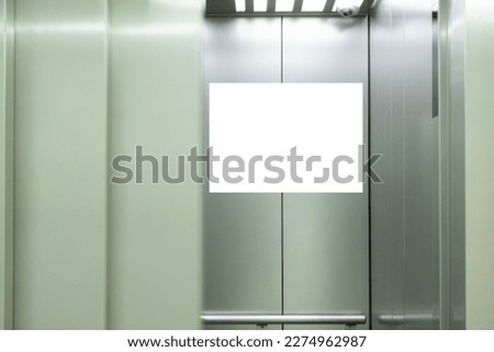 Mock up. Vertical poster media template frame hanging on the wall inside elevator lift
