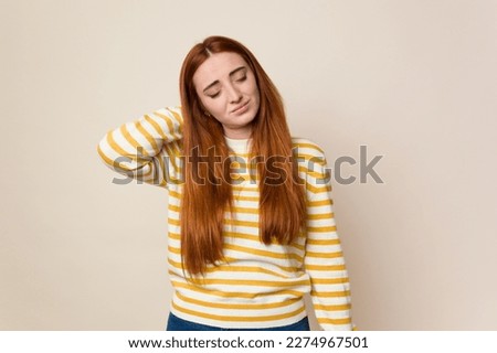Young red hair woman isolated having a neck pain due to stress, massaging and touching it with hand.