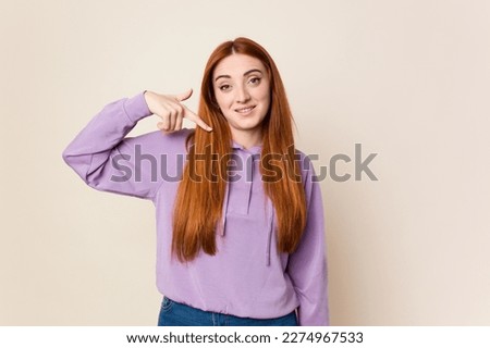 Young red hair woman isolated person pointing by hand to a shirt copy space, proud and confident