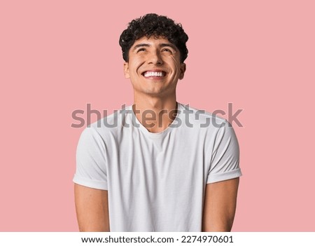 Young latin man laughs and closes eyes, feels relaxed and happy.