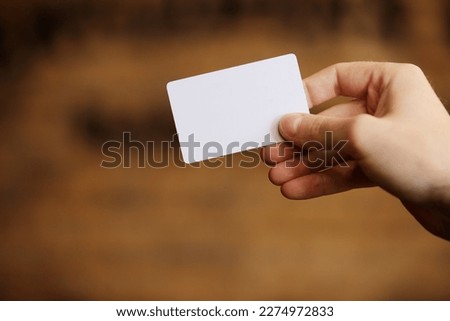 Male hand holds blank white card mockup on brick wall background. Plain call-card mock up template holding arm. Plastic credit namecard display front. Check offset card design. Business branding
