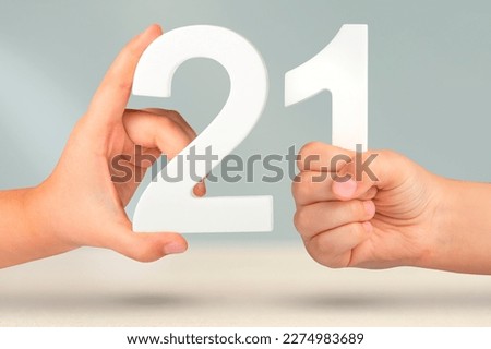 Number two one in hand. Hand holding white number 21 on blurred background with copy space. Concept with number twenty one. 21 percent, birthday 21, twenty one Royalty-Free Stock Photo #2274983689