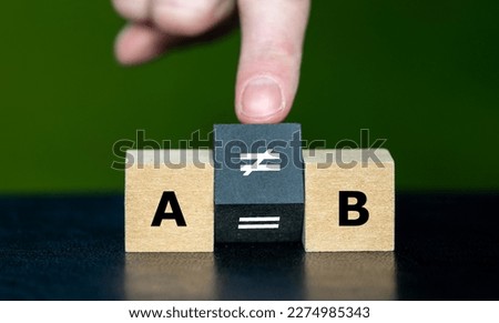 Symbol  that A does not equal B. Hand turns cube and changes the equation 'A equal to B' to 'A unequal to B'. Royalty-Free Stock Photo #2274985343