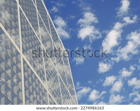 Hight futuristic glass skyscraper against blue sky. Reflection of clouds on glass 