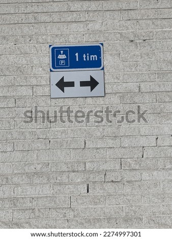 Two arrows ,One hour parking sign on mexi brick wall