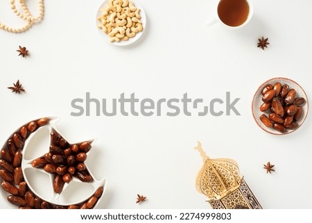 Ramadan Kareem holiday table with dates fruits plate, nuts, wooden lantern mosque, cup of tea. Royalty-Free Stock Photo #2274999803