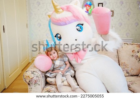 Cute little girl with an animator in a unicorn unicorn . A surprise for a child's birthday.