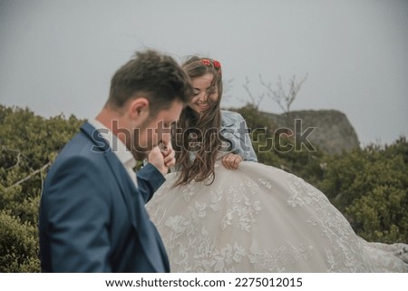 Happy wedding couple in the mountains. The groom leads the bride downstairs by the hand. She smiles sincerely. Wedding photo session in nature. Photo session in the forest of the bride and groom.