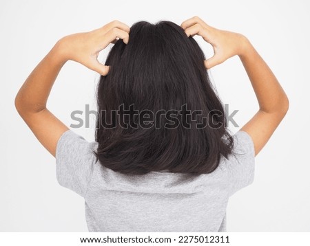 Little girl is scratching her head on white background. Closeup photo, blurred.