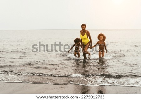 African sisters twins running on the beach with smiling mother - Focus on right girl face Royalty-Free Stock Photo #2275012735