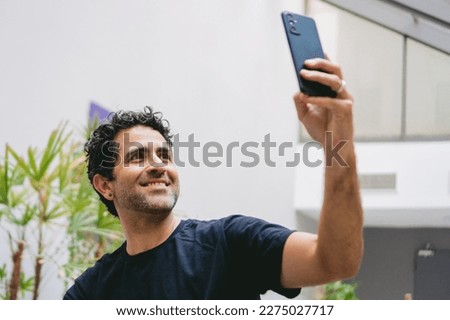 Middle-aged Latin man taking a selfie in the lobby of the hotel where he is staying.