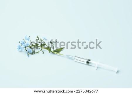 Injection syringe and flowers on blue background. Beauty Injections, vaccine creative concept. Healthcare and medical cosmetology. Royalty-Free Stock Photo #2275042677