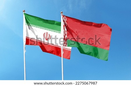 Iran flag and Belarus flag on cloudy sky. waving in the sky Royalty-Free Stock Photo #2275067987