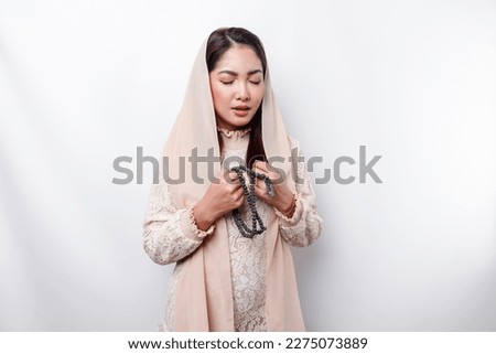 Religious beautiful Asian Muslim girl wearing a headscarf praying to God.