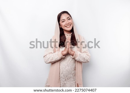 Portrait of a young beautiful Asian Muslim woman wearing a hijab gesturing Eid Mubarak greeting Royalty-Free Stock Photo #2275074407