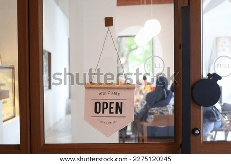 Store sign showing that it is open, Open restaurant sign hit on the glass door.