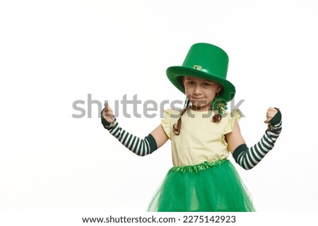 Adorable Irish little girl in Leprechaun carnival costume for St. Patrick's Day, thumbing up looking at camera, isolated on white background. Culture and traditions in Ireland. People and life events