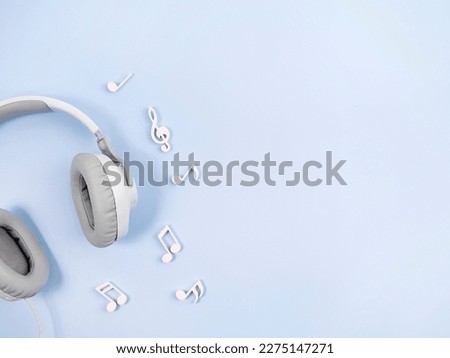 Headphones with notes on a blue background. The concept of listening to music.