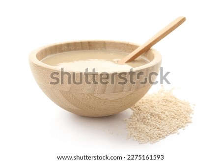 Wooden bowl with tasty tahini and sesame seeds on white background Royalty-Free Stock Photo #2275161593