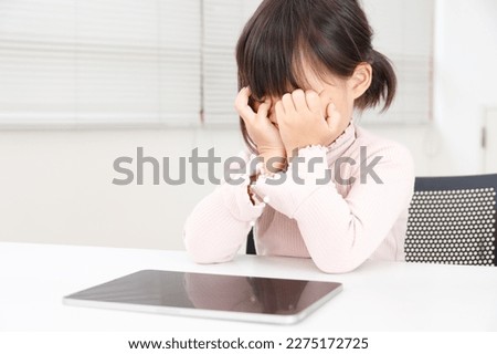 An Asian child whose eyes are tired from studying or playing games on a tablet. The child is rubbing their eyes. Royalty-Free Stock Photo #2275172725