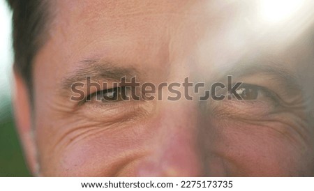 One happy man macro portrait face close up smiling outside with sunlight flare. 40s person with wrinkles closeup of eyes Royalty-Free Stock Photo #2275173735