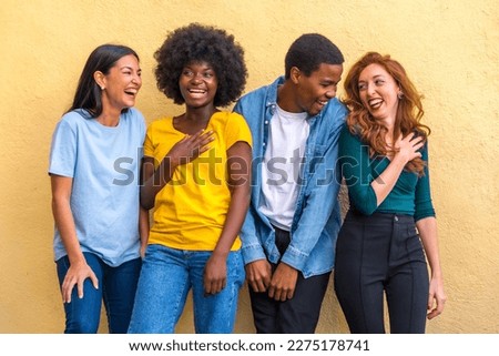 Multi ethnic friends against yellow wall having fun smiling, international youth community