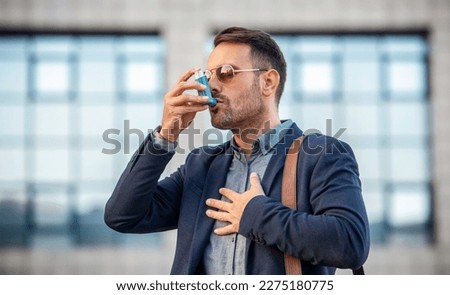 Stress and asthma. Young businessman treating asthma attack with inhaler. Health care concept Royalty-Free Stock Photo #2275180775