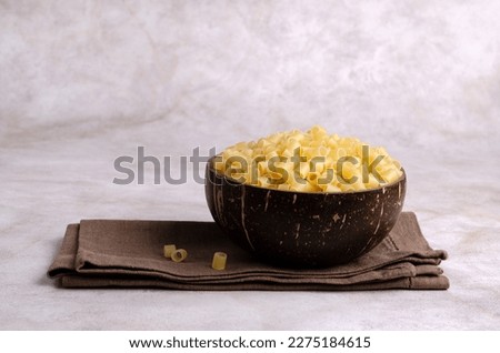 Traditional Italian dry pasta in a wooden bowl on a light background. Copy space. Selective focus.