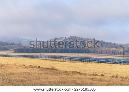 Photovoltaic solar cell panels against the backdrop of an autumn forest and mountain in the fog. Renewable energy source. Green energy concept. Solar power generation. Sustainable resources