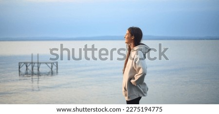 Young sportive girl standing by sea and looking at view.