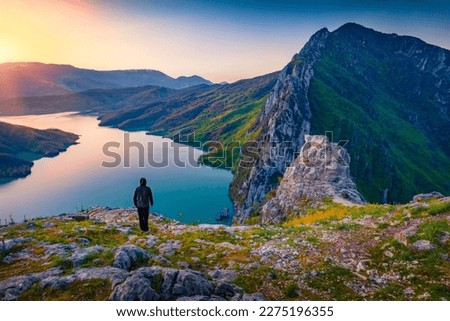 Tourist meets the sunrise on the edge of a cliff on Bovilla Lake, near Tirana city located. Spectacular spring landscape  of Albania, Europe. Beauty of nature concept background. Royalty-Free Stock Photo #2275196355