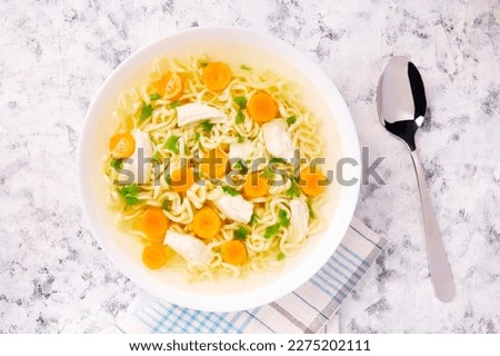 Homemade chicken soup with noodles and vegetables in a white bowl,on a gray  background. Healthy warm comfortable food.