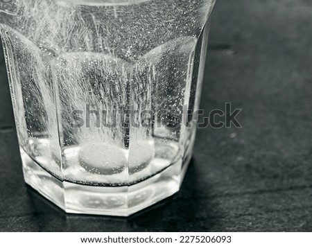 White effervescent tablet in glass with water on table. Pill dissolving in glass of water. Soluble pill, an effective remedy