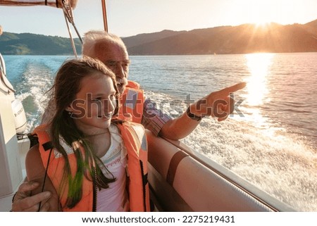 Granddaughter listening to her grandfather while they enjoy a boat ride at the sunset Royalty-Free Stock Photo #2275219431