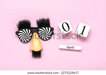 funny face - fake eyeglasses, nose and mustache, calendar with date 01 April on pink background Happy fools day concept  1st April party Holiday greetind card