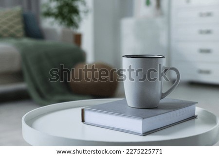 Ceramic mug and book on white table indoors. Mockup for design