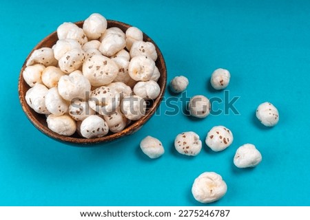  Organic Crispy Lotus pops Seeds or Phool Makhana served in a wooden bowl on background.