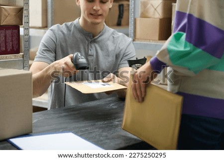 Woman and post office worker with scanner reading parcel barcode at counter indoors, closeup Royalty-Free Stock Photo #2275250295