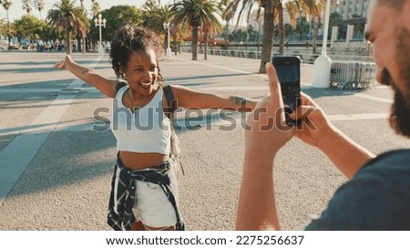 Smiling interracial couple. Man takes picture and video of woman on the phone