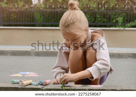 Little child drawing balloons with chalk on asphalt, space for text