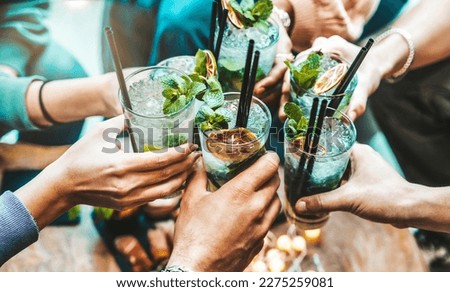 Happy friends group cheering mojito drinks at fancy bar restaurant - Young people having fun toasting cocktail glasses enjoying happy hour at rooftop pub - Party time, life style and youth concept Royalty-Free Stock Photo #2275259081