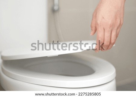 close up hand of a woman closing the lid of a toilet seat. Hygiene and health care concept. Royalty-Free Stock Photo #2275285805