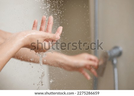A woman uses hand to measure the water temperature from a water heater before taking a shower Royalty-Free Stock Photo #2275286659