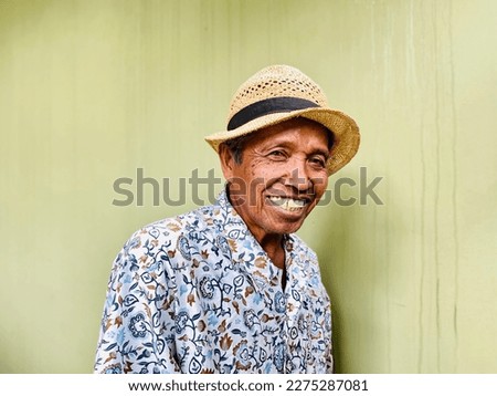 Elderly Asian Man Wide smile listen story of the day wearing hat and batik Clothes. #Uniquesself Royalty-Free Stock Photo #2275287081
