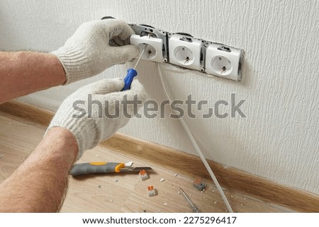 Installing electrical wall outlets with a screwdriver in a new home.                             Royalty-Free Stock Photo #2275296417