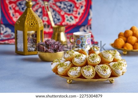 Arabian pancake Qatayef with qishta cream and pistachio . Traditional sweets with ramadan decor                               Royalty-Free Stock Photo #2275304879